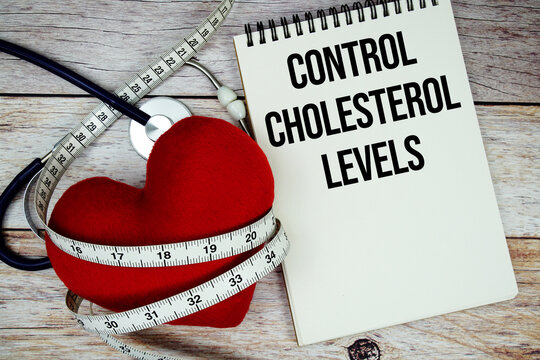 Control Cholesterol Levels text with stethoscope and wrap a measuring tape around red heart on wooden background