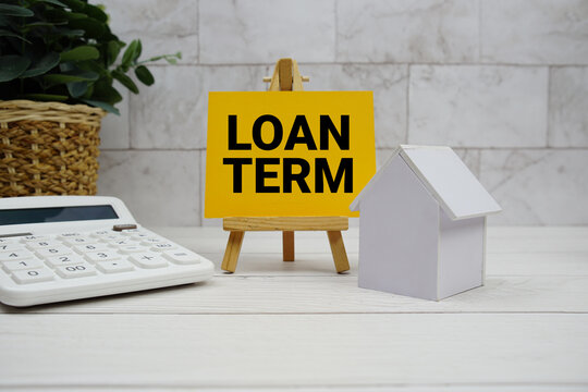 Loan Term text with house model and calculator on wooden background