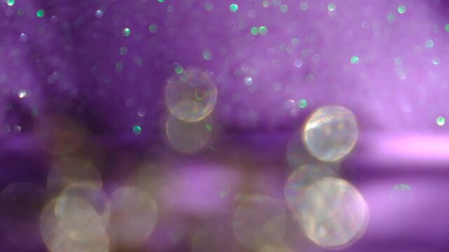 Christmas decorations defocused. Luxury golden purple backdrop. Glittering abstract flares bokeh background. Lavender and violet coloring. Blurry abstract fairy light background