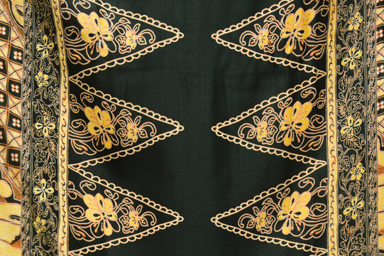Traditional Indonesian batik fabric with floral motifs and parang pattern. Black, yellow, and brown textile background for fashion and interior design.