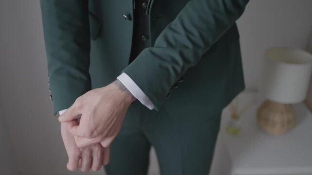 Close view of groom adjusting jacket sleeve and cuff preparing formal wedding attire