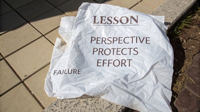 Crumpled Paper with Motivational Words on a Sidewalk Encourages Reflection, Growth, and Learning from Failure and Perspective in Daily Life