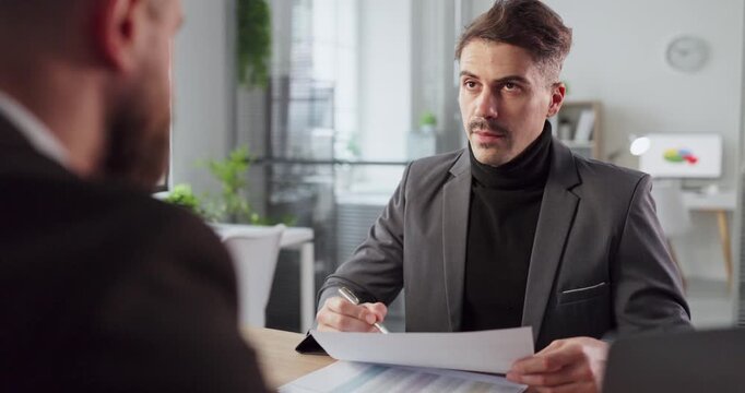 Client and manager in office meeting reviewing document. Focused discussion of contract terms and finance, with notes captured at a modern desk. Clear concept of business consultation trust.