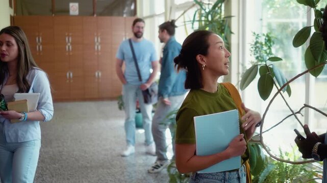 Diverse group of university students standing and talking in campus hallway during break. Friendly social interaction and relaxed student atmosphere indoors.