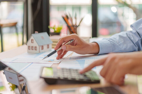 Side View with House Model, Asian Male 30-40s Real Estate Agent Analyzing Market Charts in Thailand Office