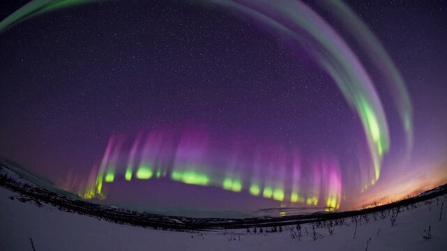 Colorful twilight with northern lights, Spectacular cosmic display over cold wilderness and distant settlements, Magnificent celestial event casting vibrant hues across frozen plain at twilight