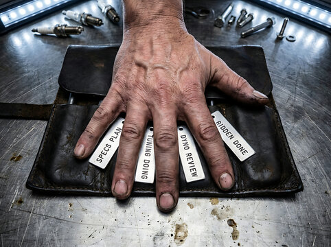 Close-up of a mechanic's hand resting on a leather tool roll, illustrating a detailed engine tuning process with organized tasks for precision automotive work