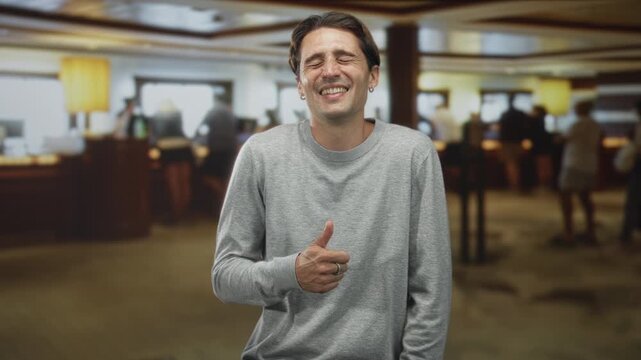 Man gives thumbs up with right hand at airport check-in counter while smiling and pointing to the side; cheerful confidence.