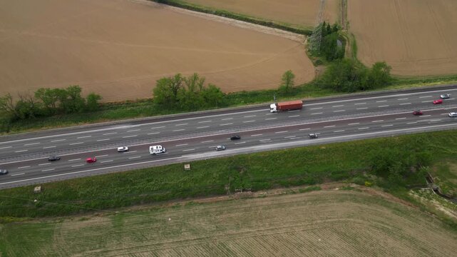 Highway Transportation: An aerial view of a busy highway with multiple lanes, highlighting the constant flow of vehicles, including a large truck, as they traverse the expanse of the road.