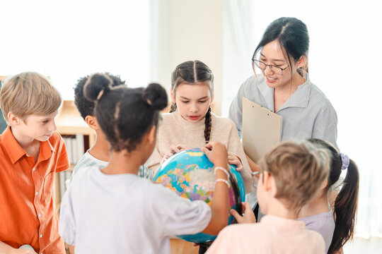 Back to school and education concept of diverse schoolchildren study globe with teacher in bright classroom