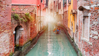 Venetian gondolier punting gondola through green canal waters of Venice Italy © muratart