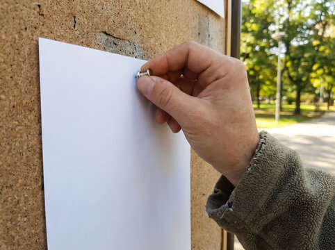 Hand pinning a blank flyer on a community board for International Missing Children&rsquo;s Day