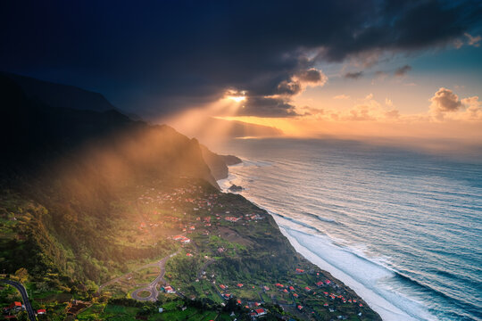 Dramatic Landscape of Madeira Island with Golden Sun Rays Piercing through Clouds over the Atlantic