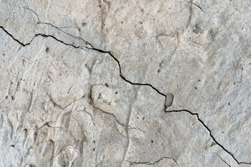 One big diagonal crack on a bumpy concrete grey wall surface macro © Tanaly
