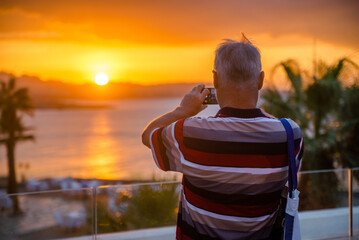 Fototapeta premium A man takes pictures of the sunset over the Red Sea 