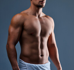 Obraz premium Abs, towel and man in studio for fitness, body care and core muscle development on background. Bodybuilder, athletic person and strong chest with six pack growth, stomach and health for wellness
