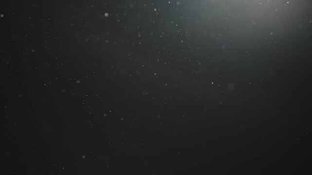Real dust particles floating mid air over dark background