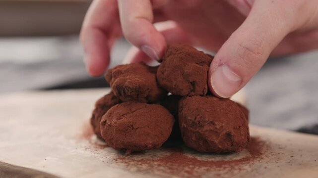 Slow motion orbit shot of man hand put handmade chocolate truffles on a wood board