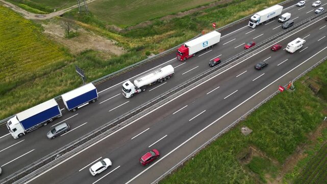 Highway Haulage: A bird's-eye perspective captures a multi-lane highway bustling with the constant flow of traffic. The image shows variety of trucks, cars on a busy road.
