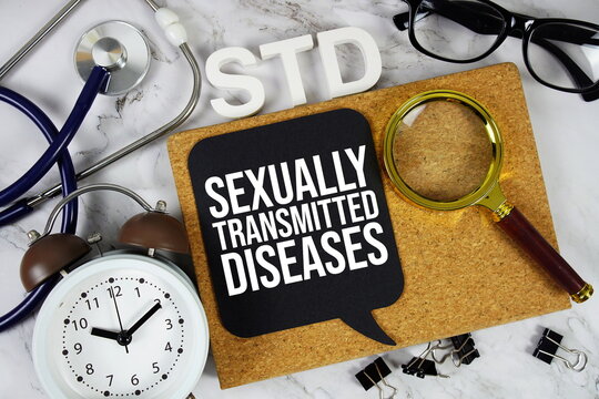 STD - Sexually Transmitted Diseases acronym with alarm clock and magnifying glass, medical and healthcare concept background