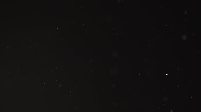Slow motion real dust particles floating mid air over dark background