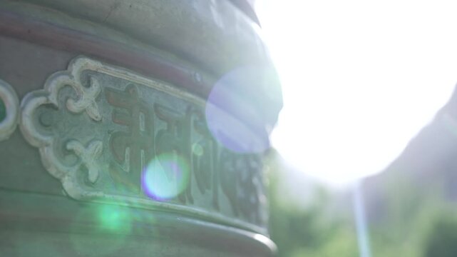 Close-Up of Ladakhi Monastery Prayer Wheel Being Spun with Warm Sun Flare
