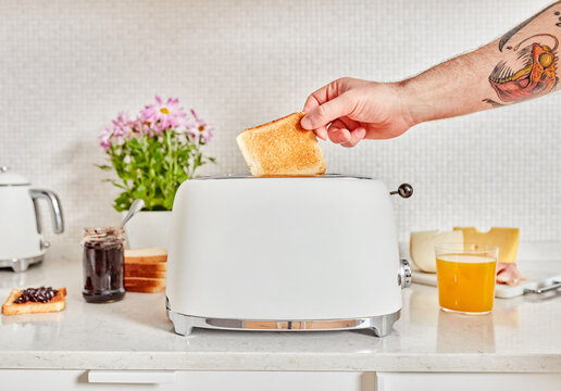 Hand taking toast from toaster, fresh breakfast moment