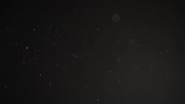 Slow motion real dust particles floating mid air over dark background