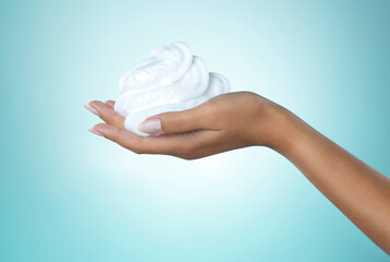 Fototapeta premium Woman, hand and foam in studio for cleaning skin, grooming and cosmetics for body care maintenance. Person, cream soap and face wash for skincare routine, wellness and hygiene on blue background.