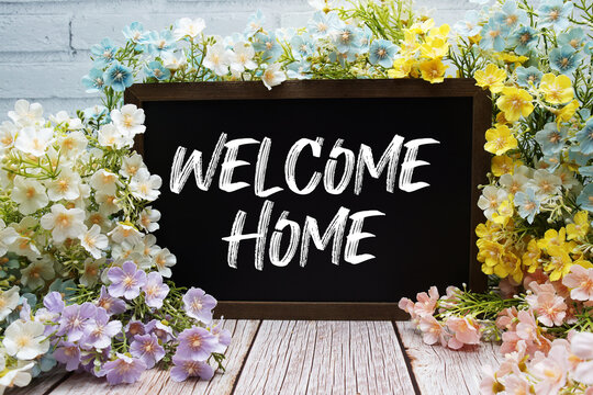 "Welcome Home" Message on Chalkboard Surrounded by Colorful Flowers
