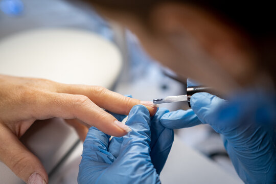 Nail care procedure in a beauty salon. Female hands and tools for manicure, process of performing manicure in beauty salon. Concept spa body care. Gloved hands of a skilled manicurist cutting cuticles