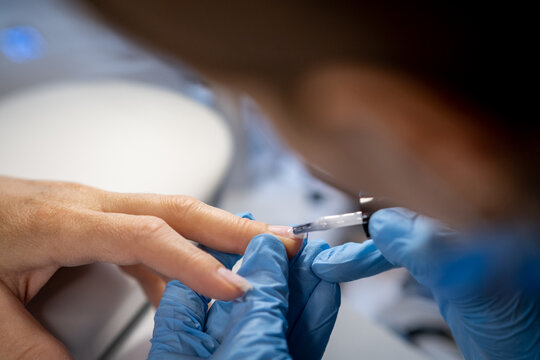 Nail care procedure in a beauty salon. Female hands and tools for manicure, process of performing manicure in beauty salon. Concept spa body care. Gloved hands of a skilled manicurist cutting cuticles