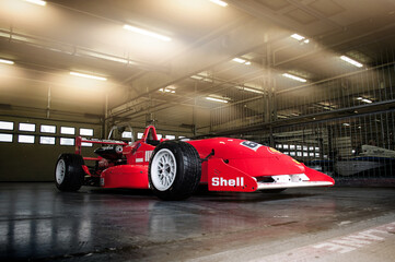 Fototapeta premium Brno, Czech Republic - April 28, 2020: Red Lola F1R formula car stands in a lit garage in the racing pit.
