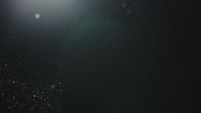 Slow motion real dust particles floating mid air over dark background