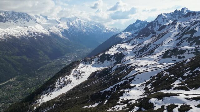 Cinematic drone flight above snowy alpine peaks overlooking Chamonix town in the valley, France, captured in slow motion