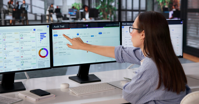 Woman Auditor Monitors Multiple Screens To Review Compliance