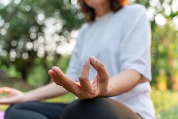 An elderly woman is meditating in a peaceful, serene garden. In the twilight of life, it's...