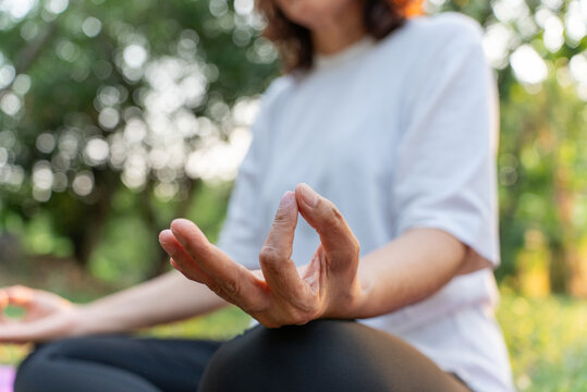 An elderly woman is meditating in a peaceful, serene garden. In the twilight of life, it's important to take care of one's physical health for longevity. Activities for senior citizens.