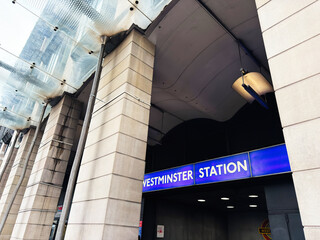 Naklejka premium Westminster Station entrance in London, UK with blue sign, canopy and urban commuters