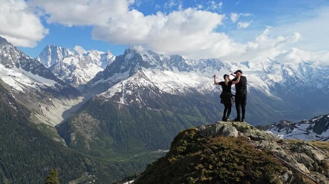 Young couple standing on a mountain summit overlooking the Mer de Glace valley in Chamonix, France, filmed in cinematic slow motion