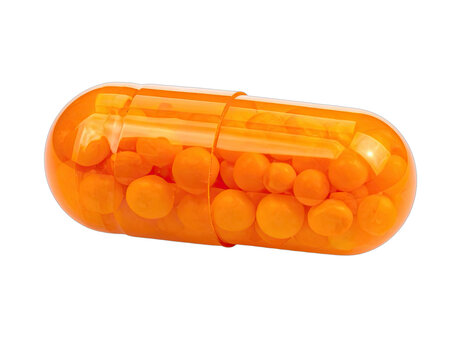 An open orange capsule reveals a multitude of small, spherical and disc-shaped orange pellets against a stark black background, suggesting medication or supplements.