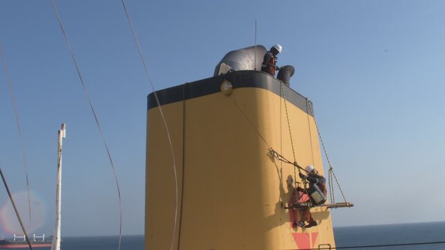 painting and maintenance work on the funnel of a cargo vessel using rope access and suspended platform