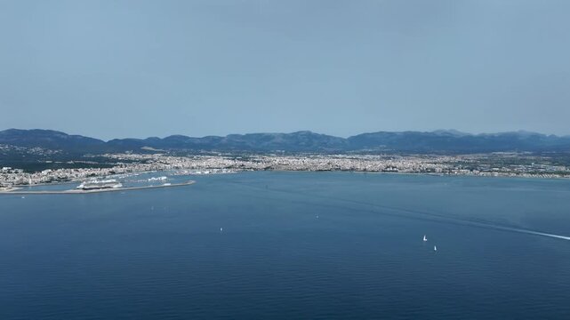 Left side cockpit window hyperlase with a view of Palma de Mallorca city and harbor, while flying over the Mediterranean sea with boats trails, and the Tramontane range at the background
