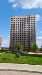 Obraz premium Modern high-rise residential building with green lawn and paved area in urban setting. Contemporary apartment complex for city living. Concept urban real estate development.
