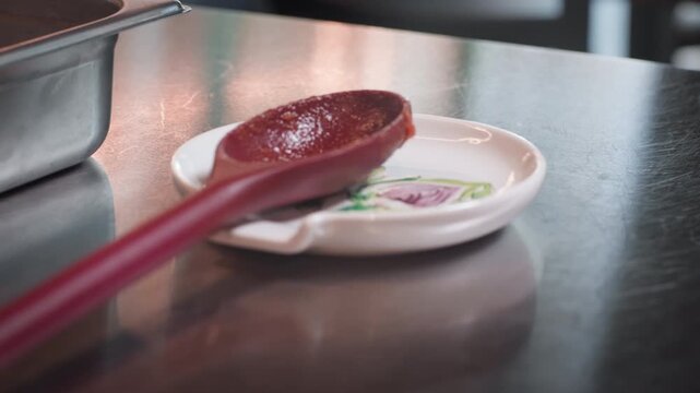 Minimalist shot of a wooden spoon resting on a stainless steel table, highlighting contrast between natural texture and industrial surface in a clean, professional kitchen setting.
