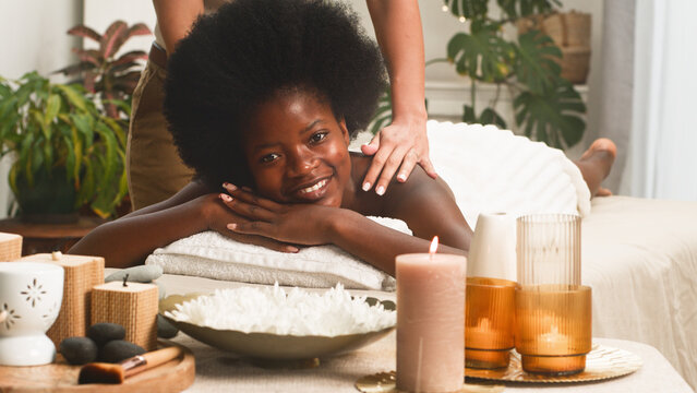 Smiling Woman Receiving Relaxing Spa Massage in Tranquil Wellness Setting With Candles