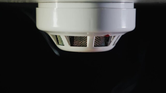 Smoke detector triggered by rising smoke in dark environment.