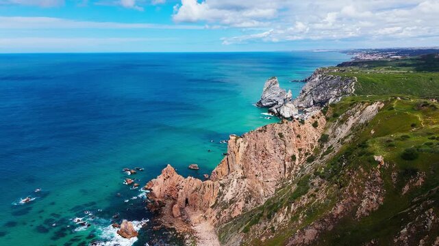 Aerial view of coastal cliffs and turquoise ocean at Praia da Ursa in Cascais, Portugal