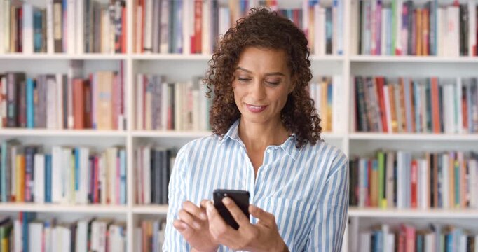 Phone, smile and woman in library for online, communication and research for books, update or author news. Happiness, scroll and person with information, about us and website for literature review