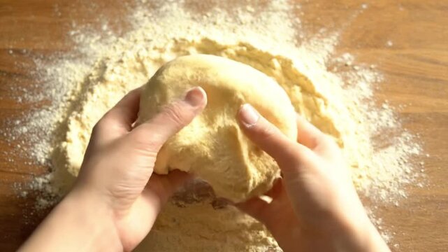 Baker Kneading Fresh Dough into a Ball on Floured Wooden Table